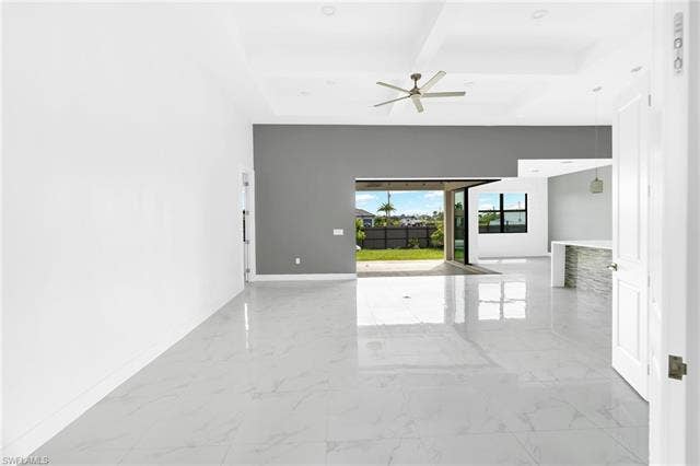 113 38 Pl, Cape Coral, FL 33993 Glossy tile flooring, tray ceiling with recessed lighting, modern ceiling fan, sliding glass doors, and a stone-clad kitchen island