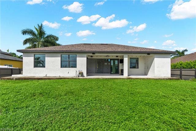 113 38 Pl, Cape Coral, FL 33993 Expansive backyard with a manicured lawn, concrete patio, and stucco exterior
