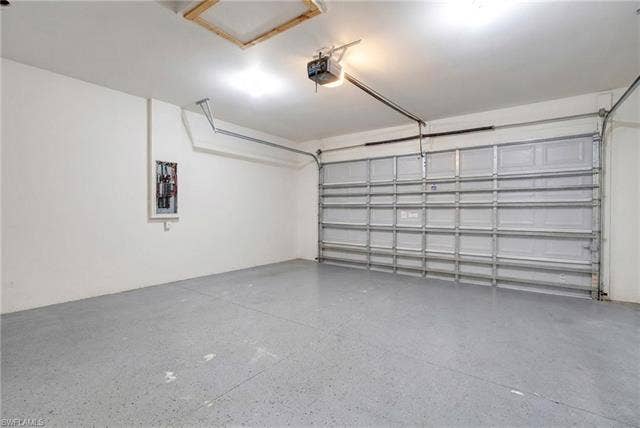 113 38 Pl, Cape Coral, FL 33993 Spacious garage featuring a durable concrete floor with an aggregate finish, a panel garage door, and an automatic garage door opener