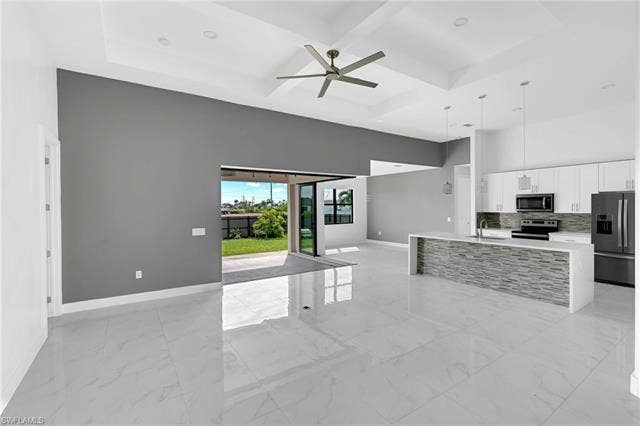 113 38 Pl, Cape Coral, FL 33993 Spacious living area featuring polished tile flooring, a tray ceiling with a modern ceiling fan, and sliding glass doors opening to the exterior
