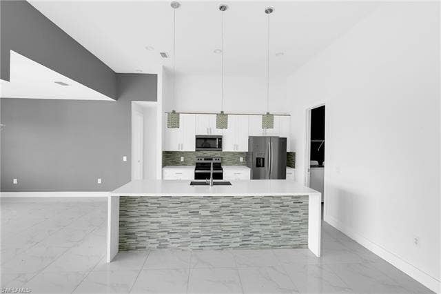 113 38 Pl, Cape Coral, FL 33993 Spacious kitchen featuring an island with a tile-finish facade, stainless steel appliances, white cabinetry, and recessed lighting
