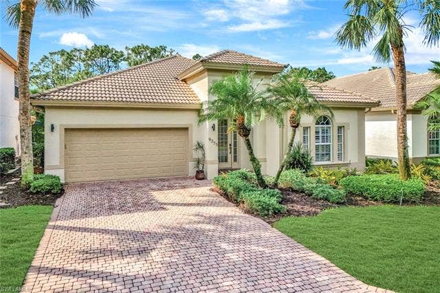 9375 Oak Strand Dr, Estero, FL 34135 Mediterranean / spanish house featuring a garage, a tile roof, decorative driveway, and stucco siding