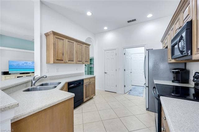 9375 Oak Strand Dr, Estero, FL 34135 Kitchen featuring visible vents, light countertops, black appliances, a sink, and light tile patterned flooring