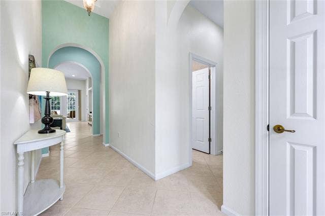 9375 Oak Strand Dr, Estero, FL 34135 Corridor featuring light tile patterned floors, baseboards, and arched walkways