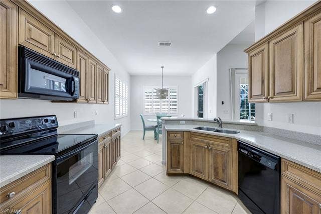 9375 Oak Strand Dr, Estero, FL 34135 Kitchen with light tile patterned floors, brown cabinets, light countertops, black appliances, and a sink