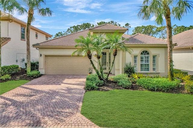 9375 Oak Strand Dr, Estero, FL 34135 Mediterranean / spanish house featuring a front yard, decorative driveway, an attached garage, and stucco siding