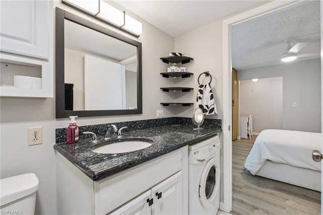 5500 Bonita Beach Rd, #308, Bonita Springs, FL 34134 Vanity with dark countertop and integrated sink, chrome faucet, and white cabinetry and washer