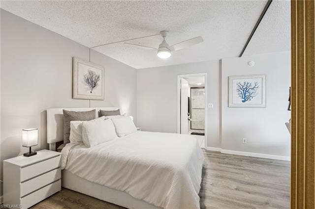 5500 Bonita Beach Rd, #308, Bonita Springs, FL 34134 Light-toned wood-finish flooring, a ceiling fan with integrated lighting, and a doorway to an adjacent bathroom with a glass-enclosed shower