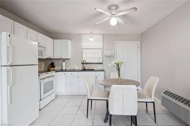 5500 Bonita Beach Rd, #308, Bonita Springs, FL 34134 Kitchen featuring white cabinetry, dark granite countertops, a mosaic tile backsplash, and white appliances