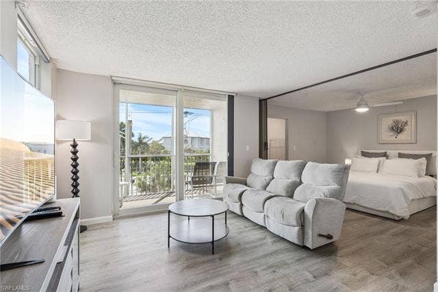 5500 Bonita Beach Rd, #308, Bonita Springs, FL 34134 Open-concept living area with wood-finish flooring, sliding glass balcony doors, and recessed ceiling lighting