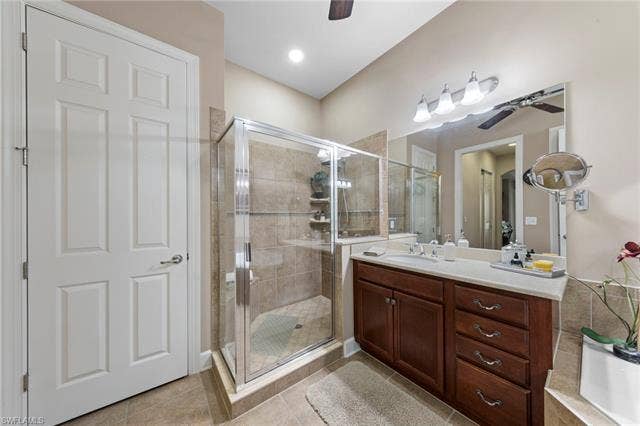 26485 Lucky Stone Rd, #202, Bonita Springs, FL 34135 Bathroom featuring a glass-enclosed shower with tile surround, a built-in vanity with rich wood-finish cabinetry, a single sink, and a large wall-mounted mirror