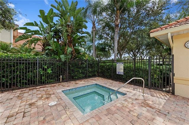 26485 Lucky Stone Rd, #202, Bonita Springs, FL 34135 Built-in spa with tiled interior, surrounded by paver decking and framed by a black metal fence