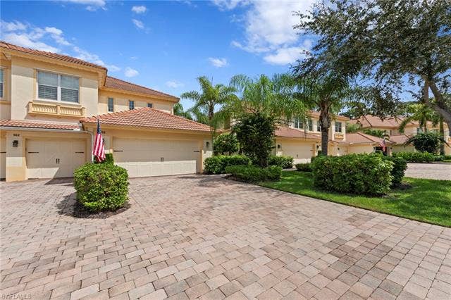 26485 Lucky Stone Rd, #202, Bonita Springs, FL 34135 Paver driveway leading to a residence with a stucco exterior, tile roof, and attached garage