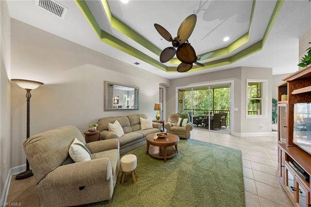 26485 Lucky Stone Rd, #202, Bonita Springs, FL 34135 Tray ceiling with accent lighting, ceiling fan, ceramic tile flooring, and sliding glass doors to a screened outdoor area