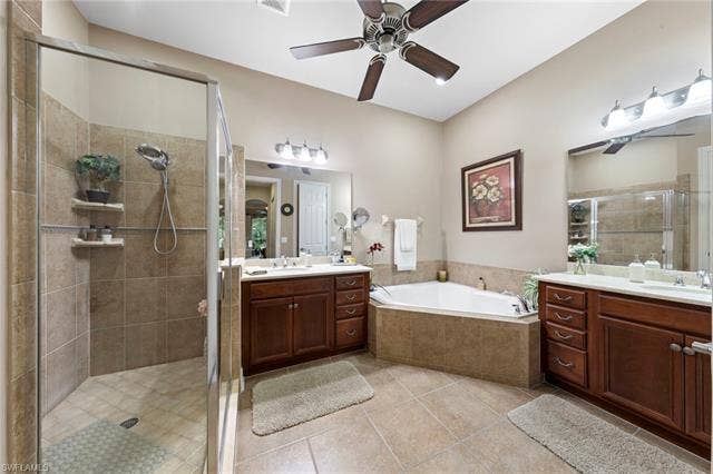 26485 Lucky Stone Rd, #202, Bonita Springs, FL 34135 Tiled flooring, dual wood-finish vanities with light countertops, built-in soaking tub, and a glass-enclosed shower with tiled walls and built-in shelving