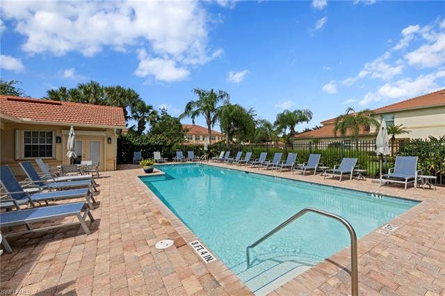 26485 Lucky Stone Rd, #202, Bonita Springs, FL 34135 Swimming pool with integrated steps, surrounded by a paver deck, and bordered by lush landscaping