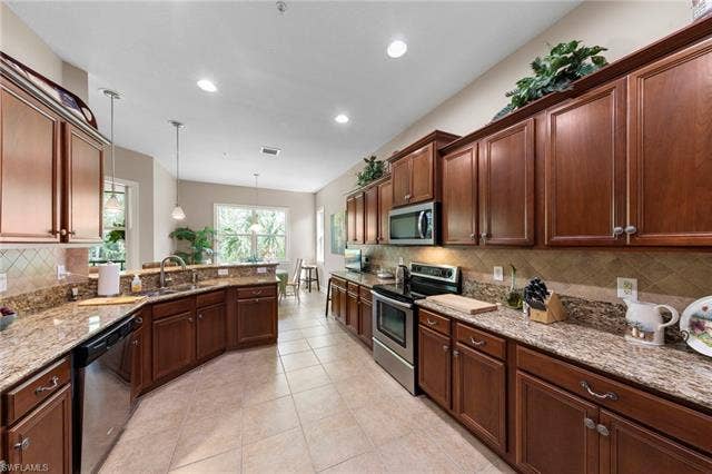 26485 Lucky Stone Rd, #202, Bonita Springs, FL 34135 Kitchen featuring wood cabinetry, stone countertops, stainless steel appliances, a tile backsplash, and recessed lighting