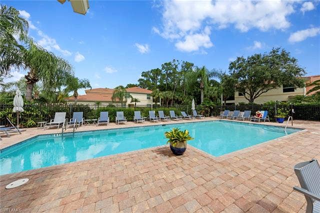 26485 Lucky Stone Rd, #202, Bonita Springs, FL 34135 Resort-style pool with a paver deck, surrounded by lush landscaping and a privacy fence
