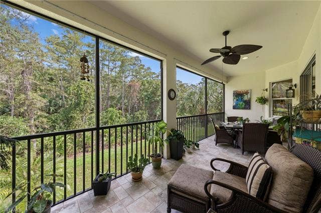26485 Lucky Stone Rd, #202, Bonita Springs, FL 34135 Expansive screened-in lanai with tile flooring, ceiling fan, and black metal railings