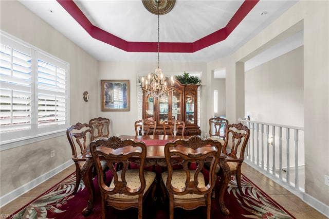 26485 Lucky Stone Rd, #202, Bonita Springs, FL 34135 Tray ceiling with contrasting accent, plantation shutters, tiled flooring, and a decorative chandelier