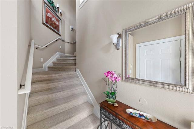 26485 Lucky Stone Rd, #202, Bonita Springs, FL 34135 Carpeted staircase with white handrails and sconce lighting