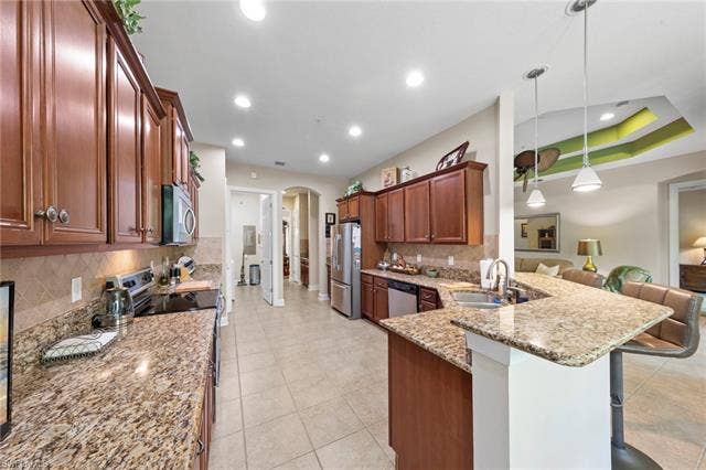 26485 Lucky Stone Rd, #202, Bonita Springs, FL 34135 Well-appointed kitchen featuring light-toned tile flooring, rich wood-finish cabinetry, substantial counter space, and stainless steel appliances