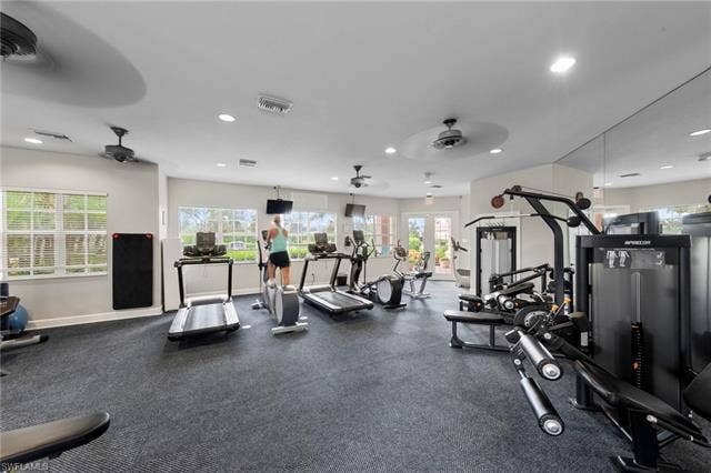 26485 Lucky Stone Rd, #202, Bonita Springs, FL 34135 Fitness center featuring cardio equipment, strength training machines, mirrored walls, ceiling fans, and multiple windows