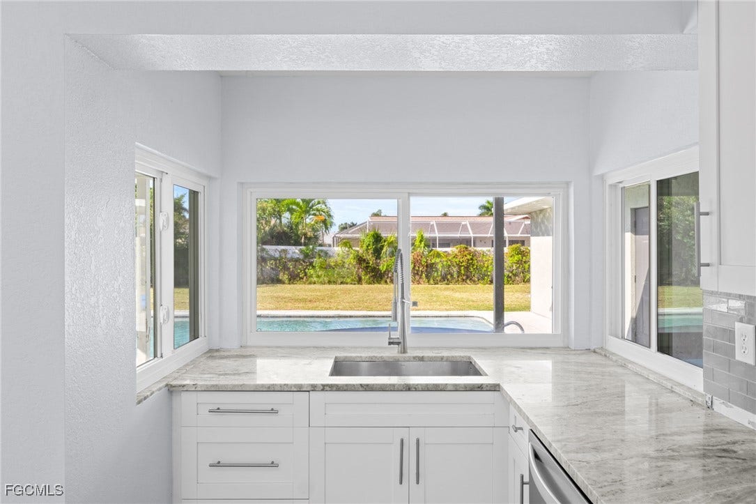 2514 SE 26th Avenue, Cape Coral, FL 33904 Kitchen featuring white cabinets, light stone countertops, healthy amount of natural light, a textured wall, and dishwasher