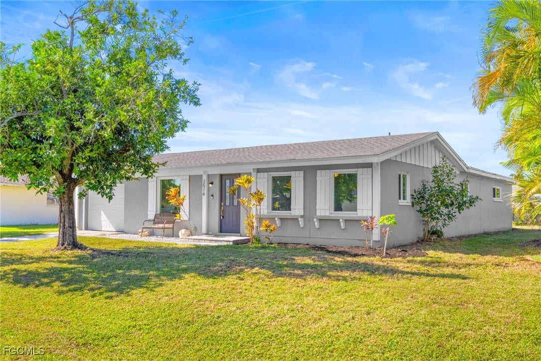2514 SE 26th Avenue, Cape Coral, FL 33904 Single story home with a front yard, a shingled roof, and a porch