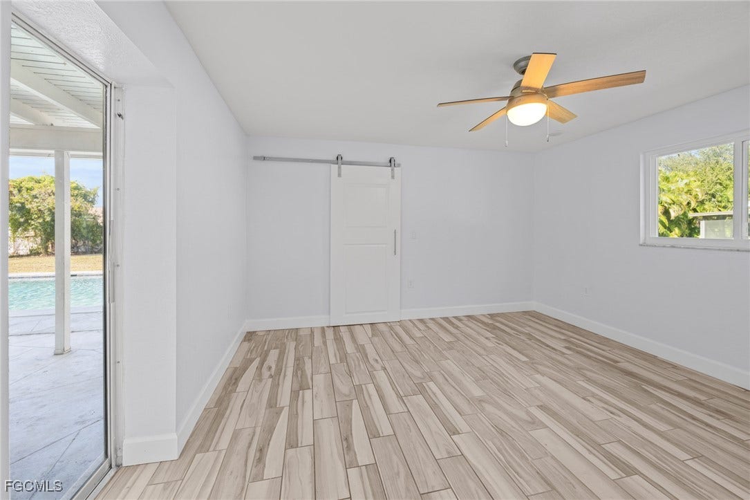 2514 SE 26th Avenue, Cape Coral, FL 33904 Spare room featuring a barn door, wood tiled floors, and ceiling fan