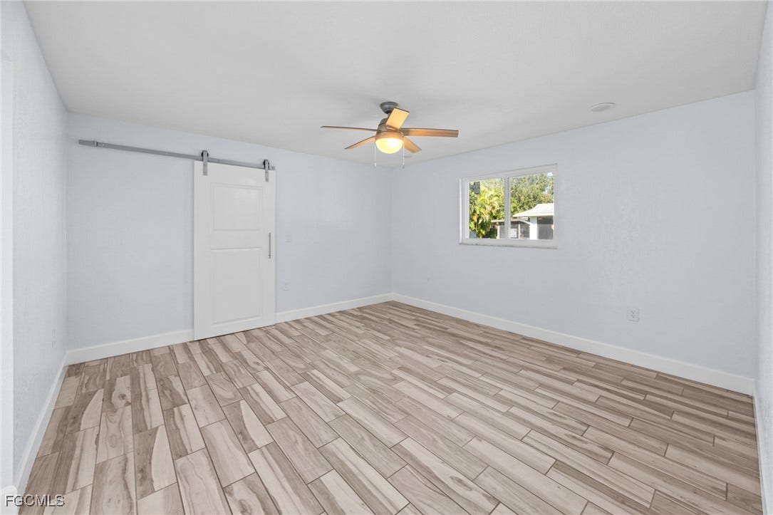 2514 SE 26th Avenue, Cape Coral, FL 33904 Unfurnished room featuring wood tiled floors, a barn door, and ceiling fan