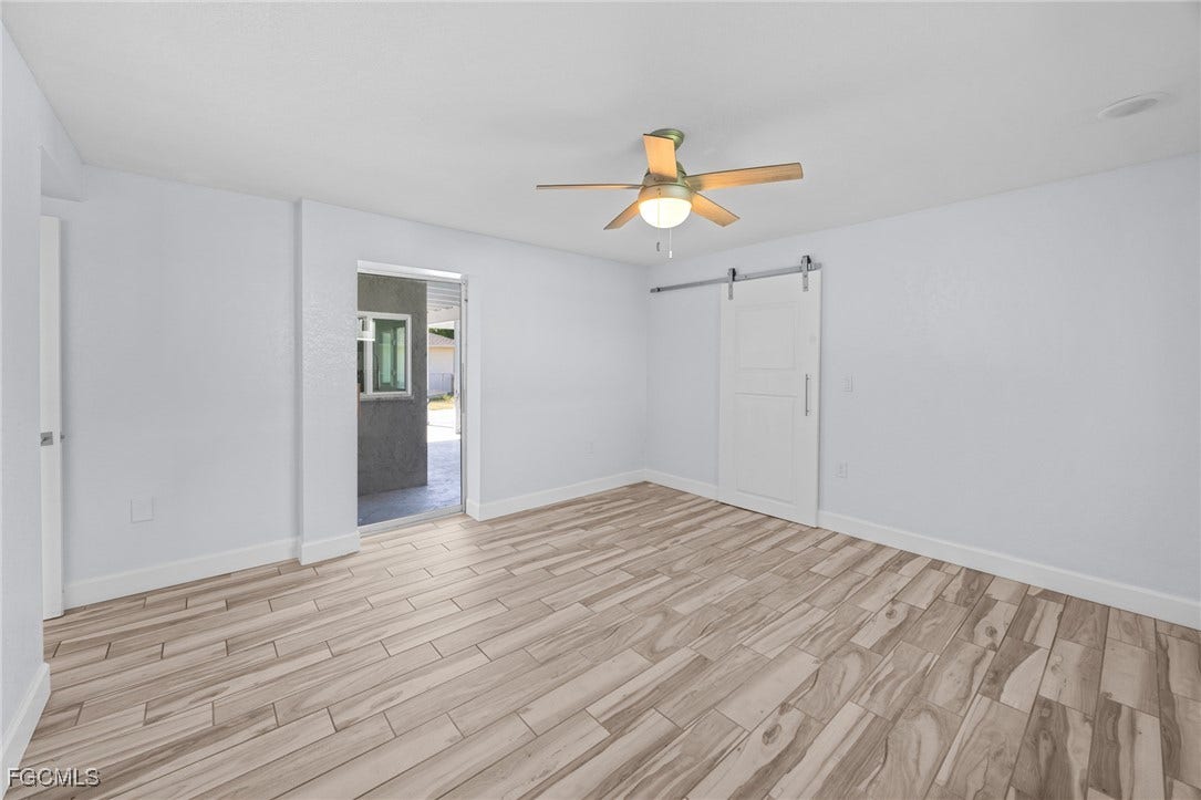 2514 SE 26th Avenue, Cape Coral, FL 33904 Spare room featuring wood finish floors, a barn door, and ceiling fan