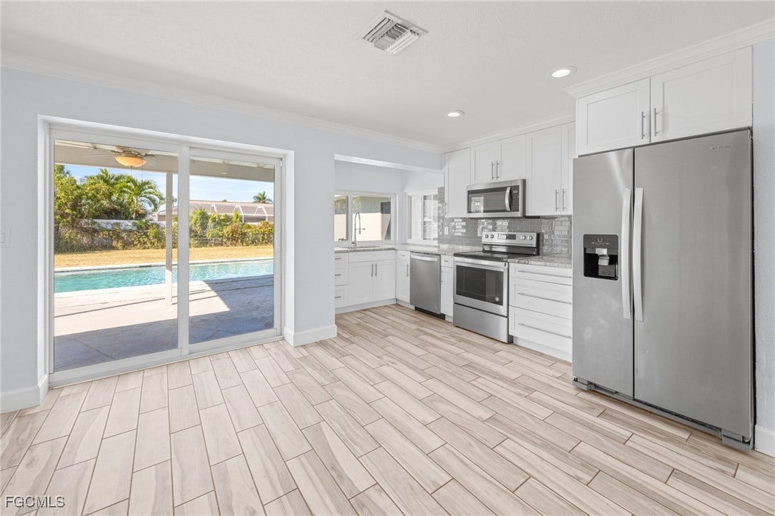 2514 SE 26th Avenue, Cape Coral, FL 33904 Kitchen featuring stainless steel appliances, white cabinets, backsplash, wood tiled floors, and ornamental molding