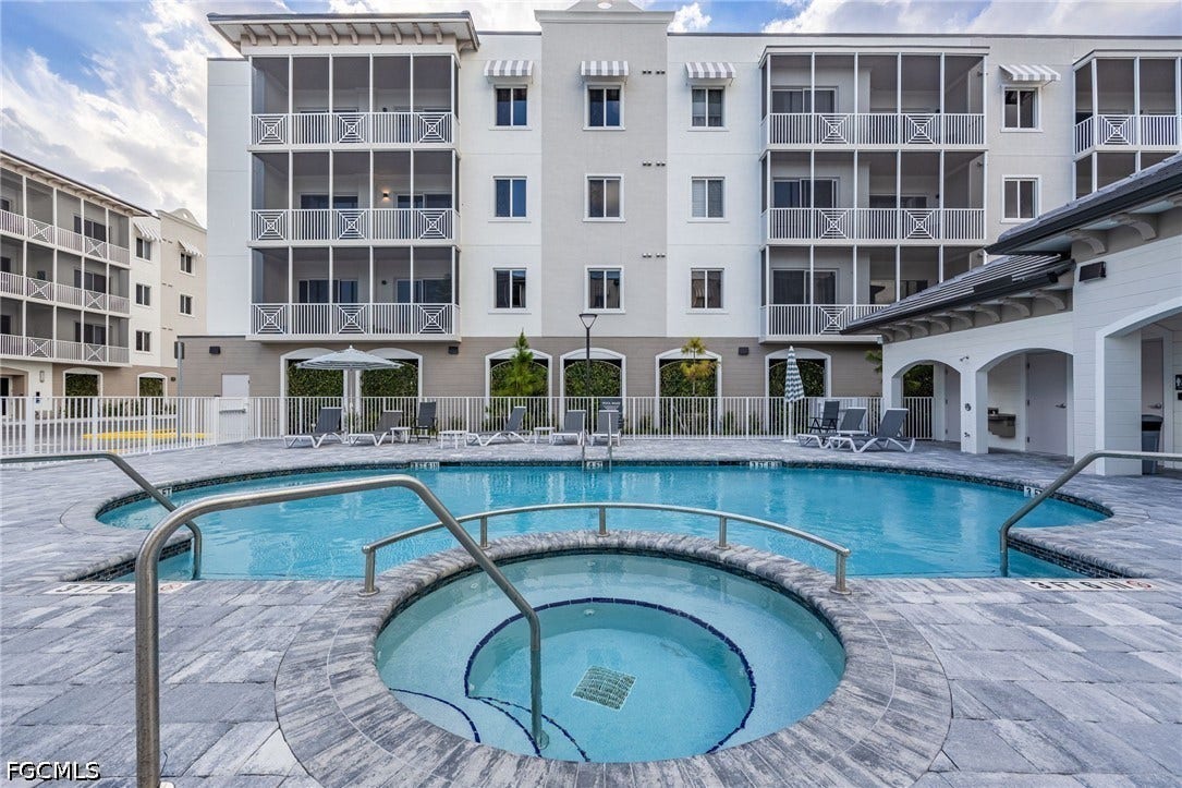 Pool featuring a community hot tub and fence