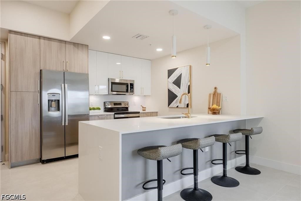 26600 ROSEWOOD POINTE Drive, #B-105, Bonita Springs, FL 34135 Kitchen featuring recessed lighting, a sink, a peninsula, a kitchen bar, and appliances with stainless steel finishes