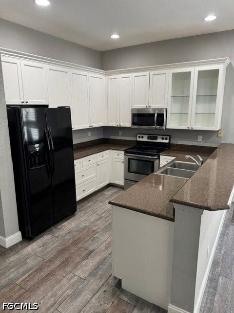White cabinetry, stainless steel appliances, wood-finish flooring, recessed lighting, and a dual-basin sink