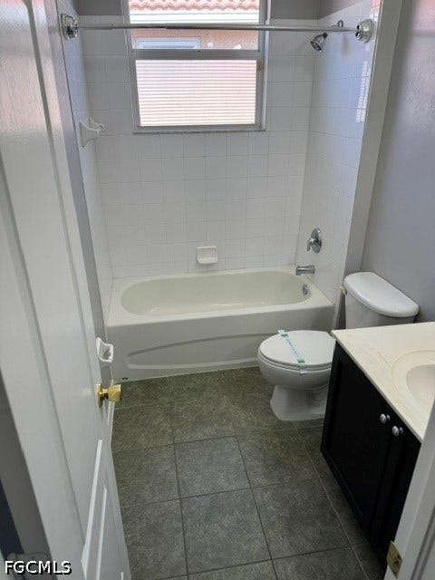 Bathroom featuring a white bathtub, ceramic tile shower surround, window with horizontal blinds, tiled flooring, and a vanity with an integrated sink