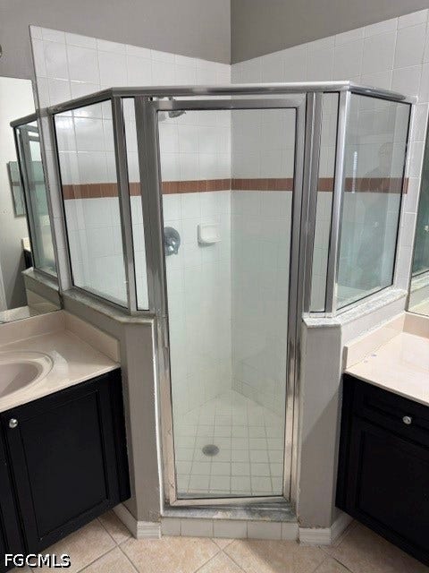 Glass-enclosed shower with white tiled walls and a decorative accent band