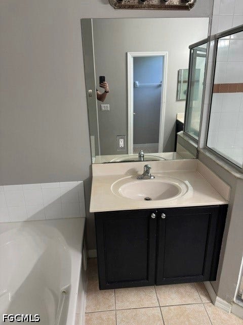 Bathroom with neutral tile flooring, a dark wood-finish vanity, a white integrated sink, and a framed shower enclosure