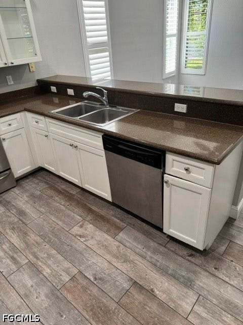 Kitchen featuring white cabinetry, dual basin stainless steel sink, stainless steel dishwasher, speckled countertops, and wood-finish flooring