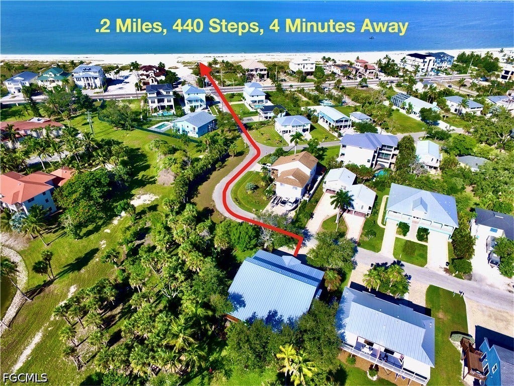 Aerial perspective showcasing a coastal neighborhood with lush landscaping and proximity to a sandy beach