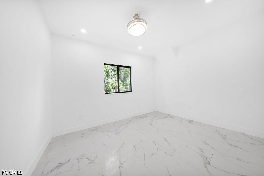 2416/2418 Joe Avenue S, Lehigh Acres, FL 33973 White walls, recessed lighting, central ceiling fixture, black-framed window, and marble-look tile flooring