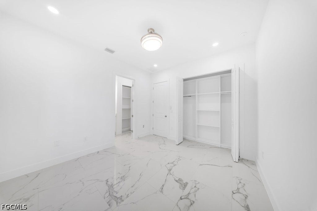 2416/2418 Joe Avenue S, Lehigh Acres, FL 33973 White tile flooring with grey veining, ceiling-mounted light fixture, recessed lighting, and built-in closet shelving