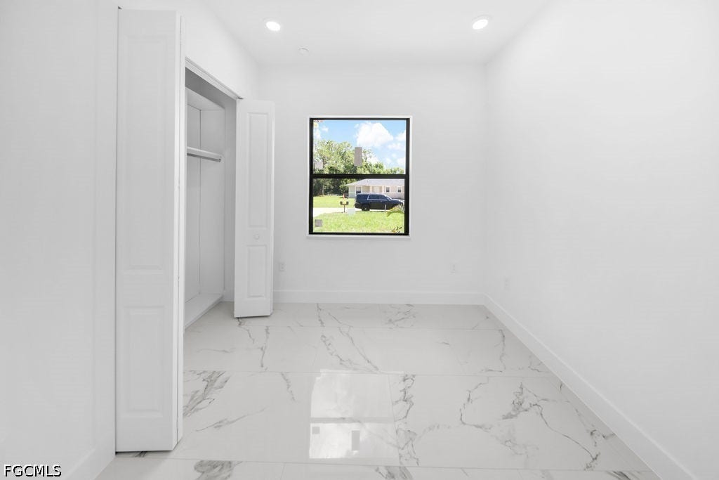 2416/2418 Joe Avenue S, Lehigh Acres, FL 33973 White walls with recessed lighting, black-framed window, and white marble-look tile flooring