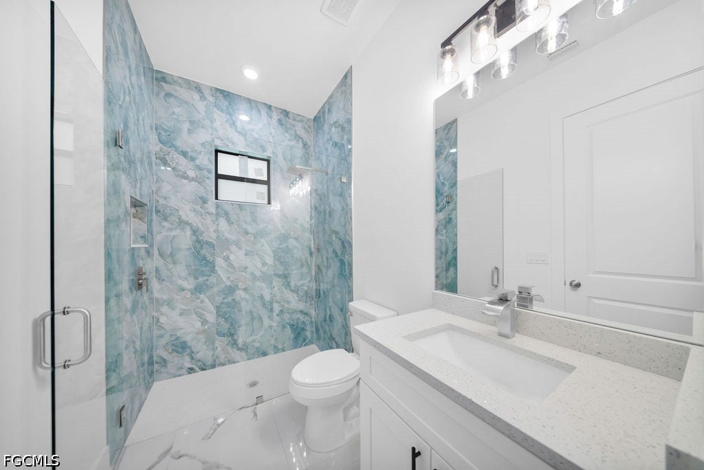 2416/2418 Joe Avenue S, Lehigh Acres, FL 33973 Glass-enclosed shower with blue-toned tile surround, built-in recessed shelf, and fixed window