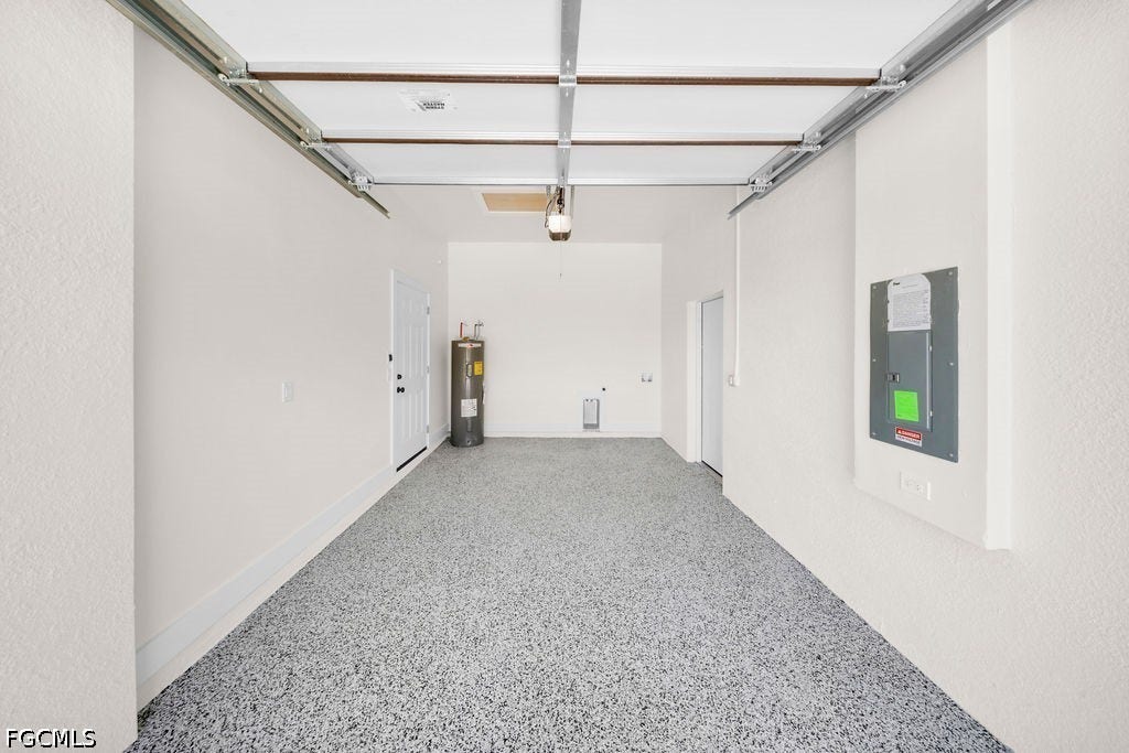 2416/2418 Joe Avenue S, Lehigh Acres, FL 33973 Garage with speckled epoxy flooring, white painted walls, and built-in utility panel