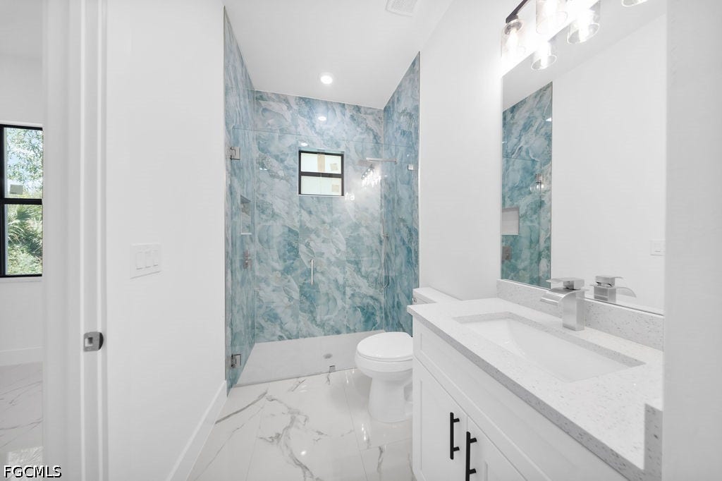 2416/2418 Joe Avenue S, Lehigh Acres, FL 33973 Contemporary bathroom featuring a vanity with a white countertop, a rectangular sink with chrome faucet, and a shower with blue-toned patterned tile surround