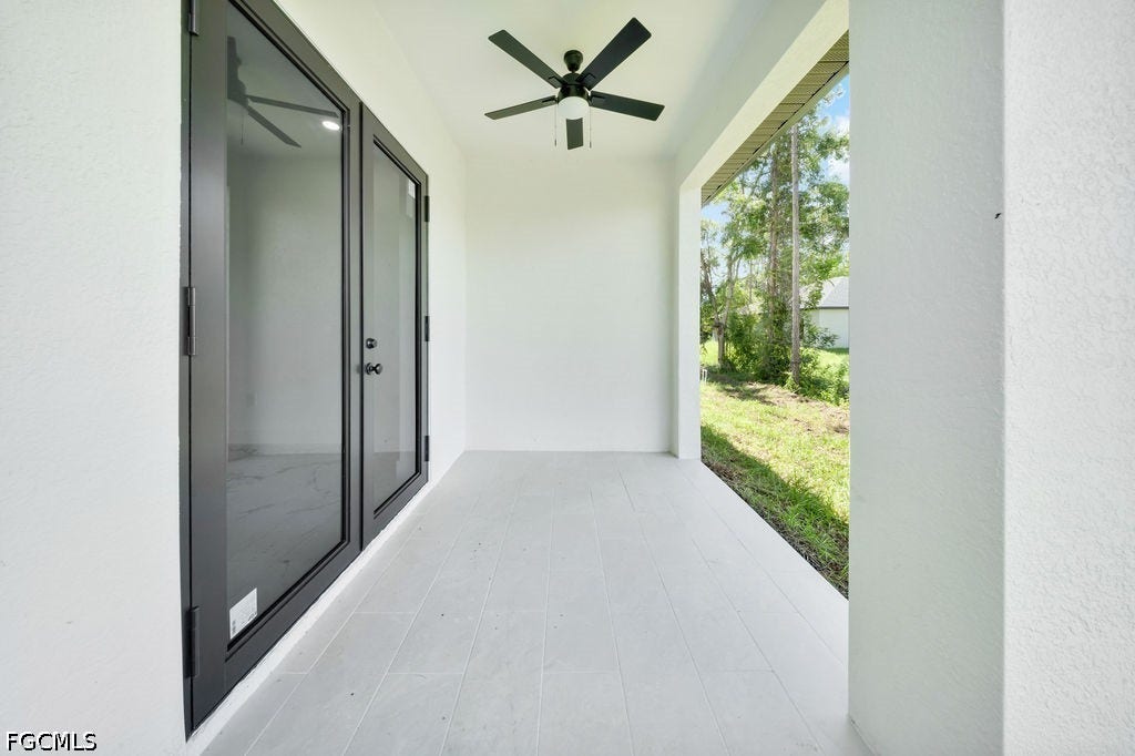 2416/2418 Joe Avenue S, Lehigh Acres, FL 33973 Covered patio featuring a ceiling fan, light-colored tile flooring, and black-framed glass doors