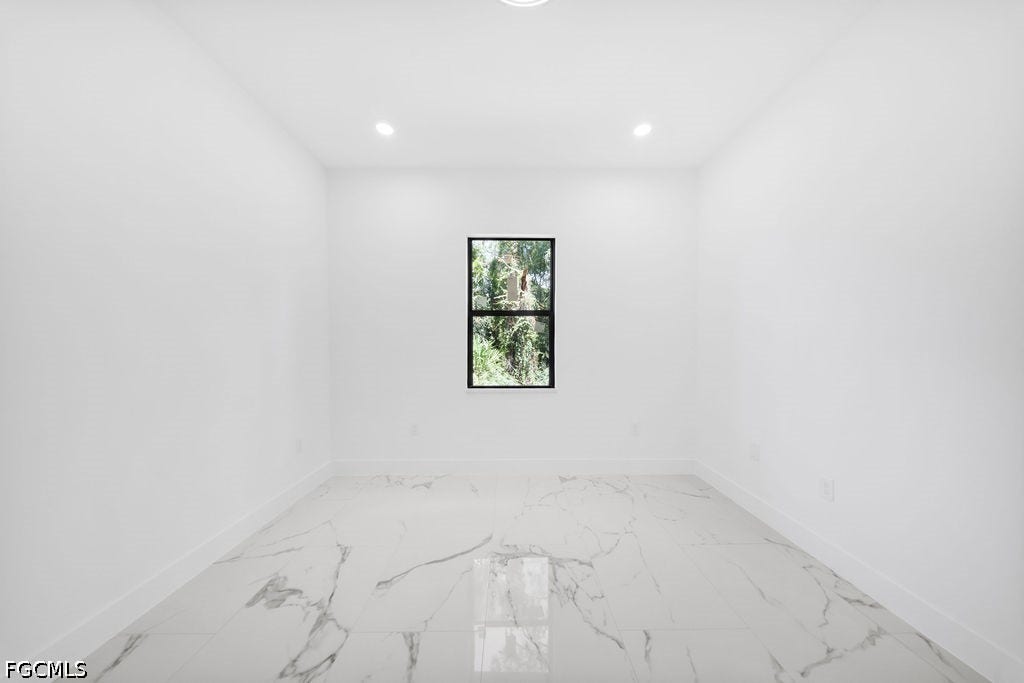 2416/2418 Joe Avenue S, Lehigh Acres, FL 33973 Recessed lighting, white walls, black-framed window, and large format white tile flooring with grey veining