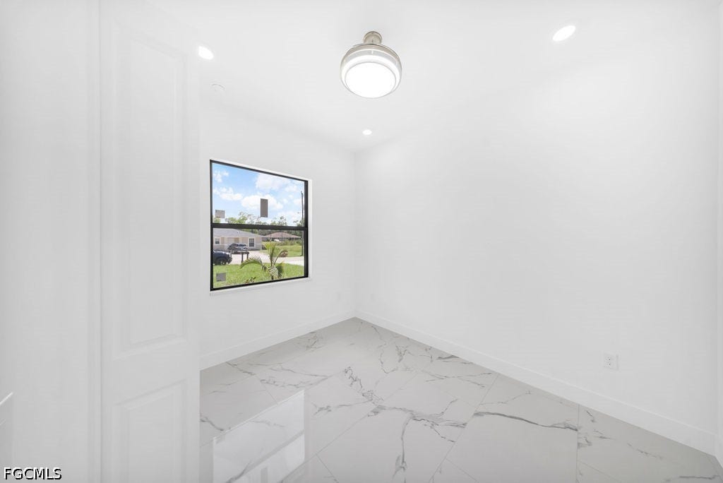 2416/2418 Joe Avenue S, Lehigh Acres, FL 33973 Recessed lighting, contemporary ceiling fixture, large window, white walls, and marble-look flooring